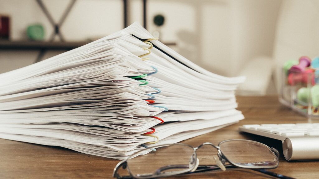 nasz regulamin, stos dokumentów leżących na biurku obok okularów