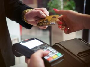 zmiana kont bankowych, ręka podająca kartę płatniczą kobiecie z terminalem